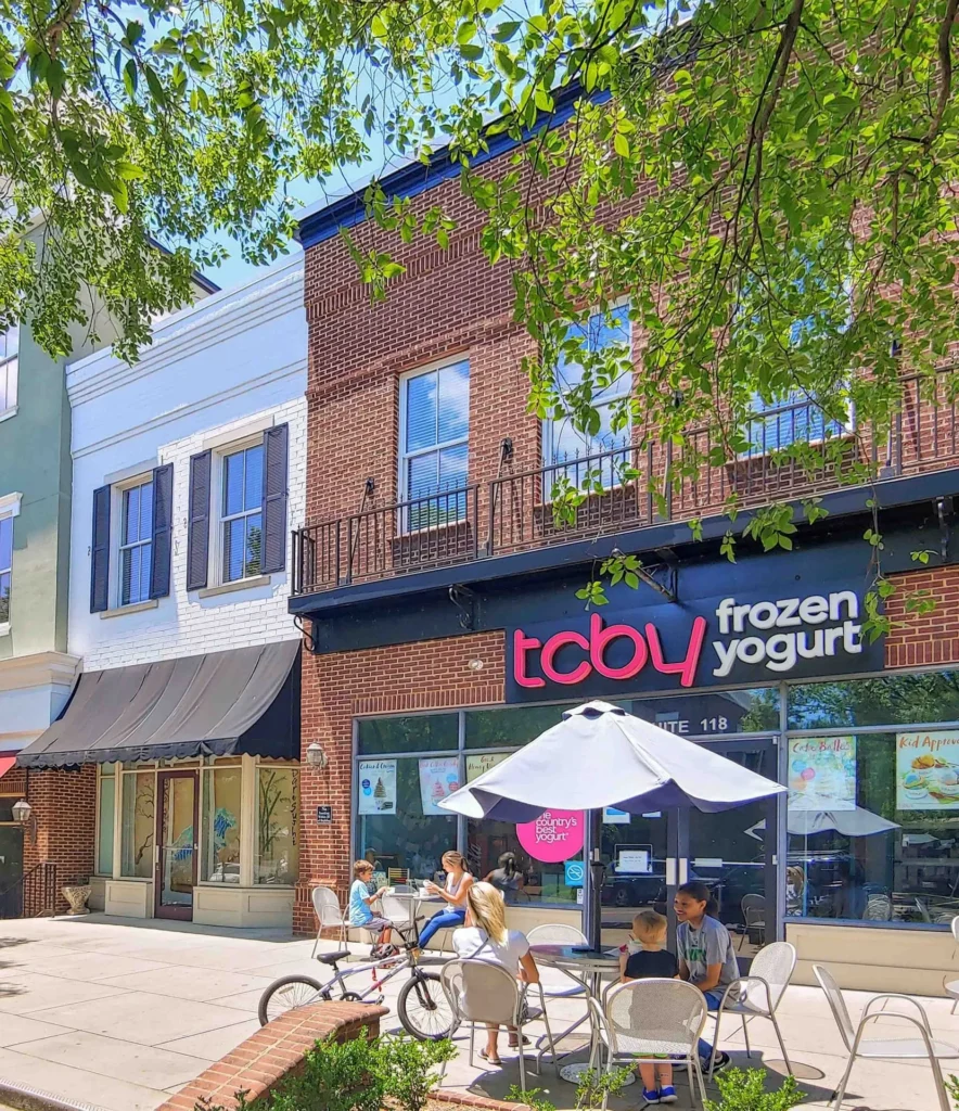 A group of people sitting at tables outside of a store