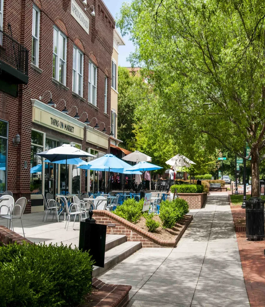 A sidewalk lined with tables and umbrellas next to a building